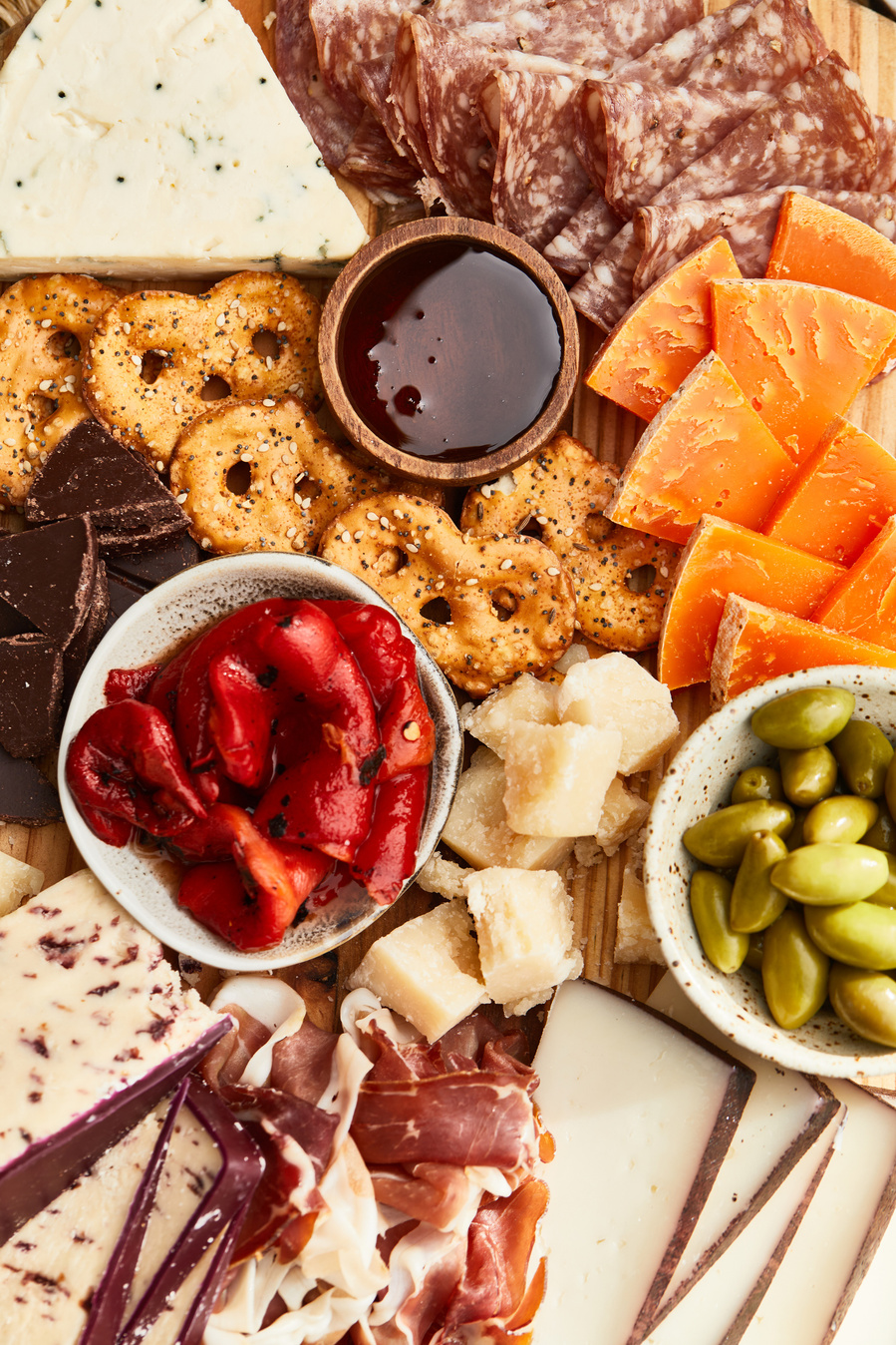 Overhead shot of colorful charcuterie board with meat, cheese, crackers, nuts, and sauce. Lifestyle food photography for The Buckle