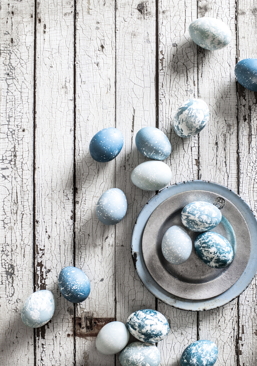 Overhead eggs photography image of dyed blue and white easter eggs on a white wood plank surface. 