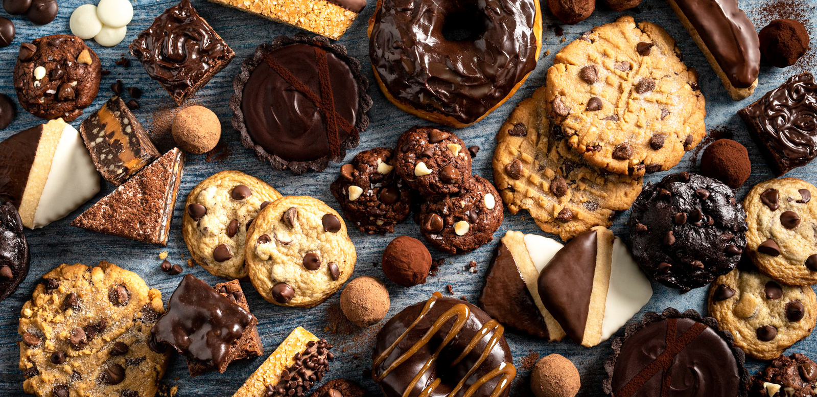 Overhead flat lay dessert images with cookies, doughnuts, brownies, and other sweets made with Ghirardelli chocolate chips. Chocolate photographer shot with heavy shadows.