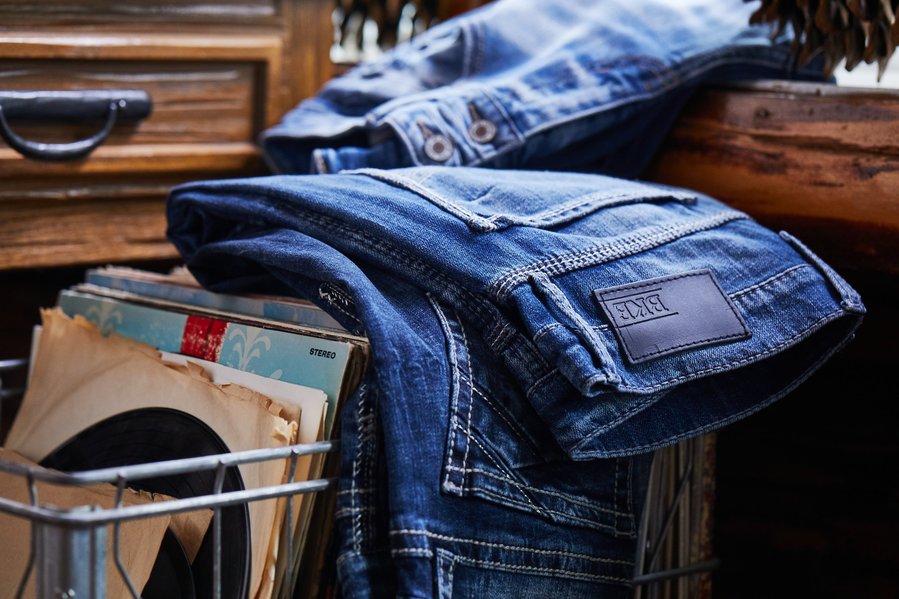 Folded blue jeans on a box of vinal records in a rustic setting. Fashion photography for the Buckle