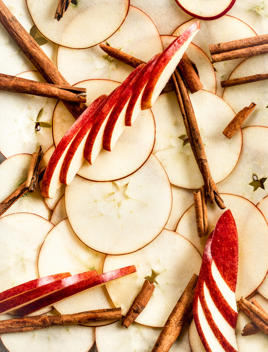 Overhead artful flat lay of sliced apples and cinnamon sticks for drink photography. 