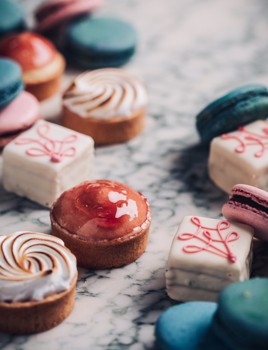 Dainty dessert food photography with pastel pink blue and white desserts on white marble tabletop