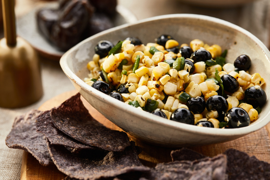 Blueberry corn salsa in a stoneware bowl with blue corn chips for outdoor brunch. Lifestyle food photography for The Buckle