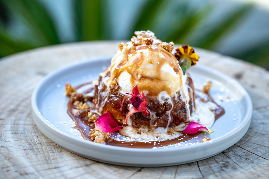 Pineapple upside-down cake a la mode with  fresh colorful flowers, melting in the sun on a restaurant patio. Restaurant food photography for the Flamingo Resort in Santa Rosa, CA