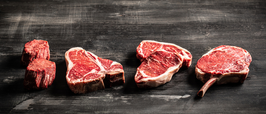 A line of raw steaks all in different cuts. Meat photography perfect for promoting the meat company's high-quality cuts of meat, inspiring customers to savor the delicious flavor and texture of their steaks.