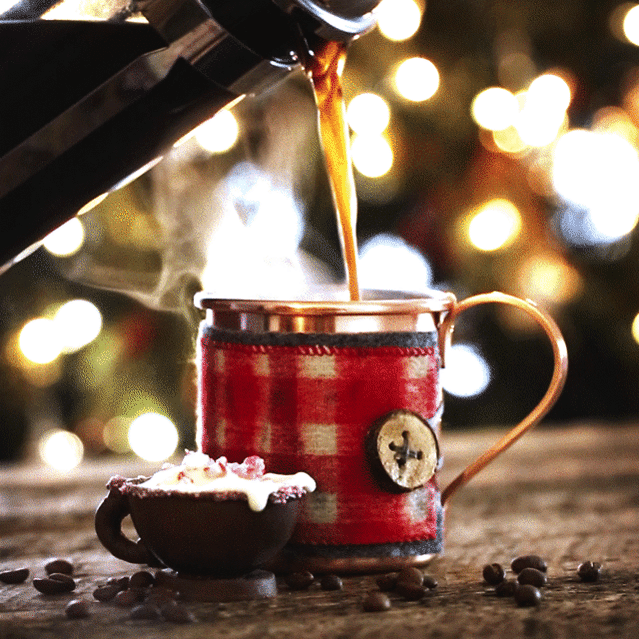 Drink photography pour shot gif or cinemograph of hot coffee being poured into a steaming copper mug with twinkle lights in the background. 