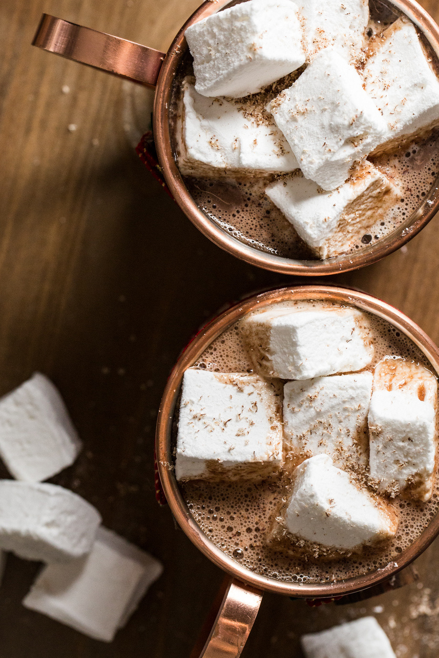 Overhead drink photography of two copper mugs filled with hot chocolate and heaped with homemade marshmallow cubes