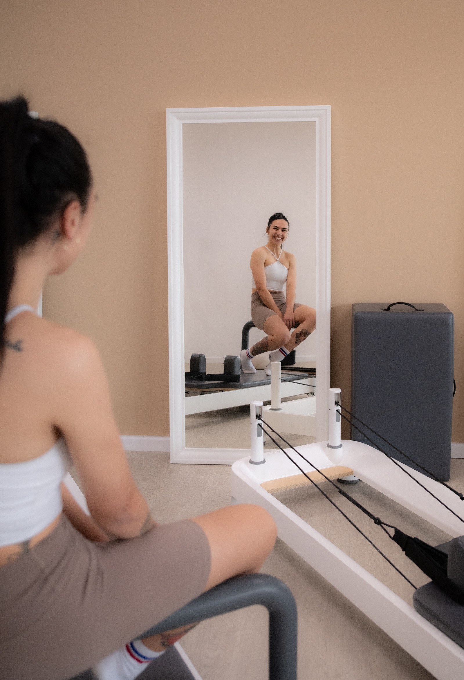 woman looking in mirror next to exercise equipment