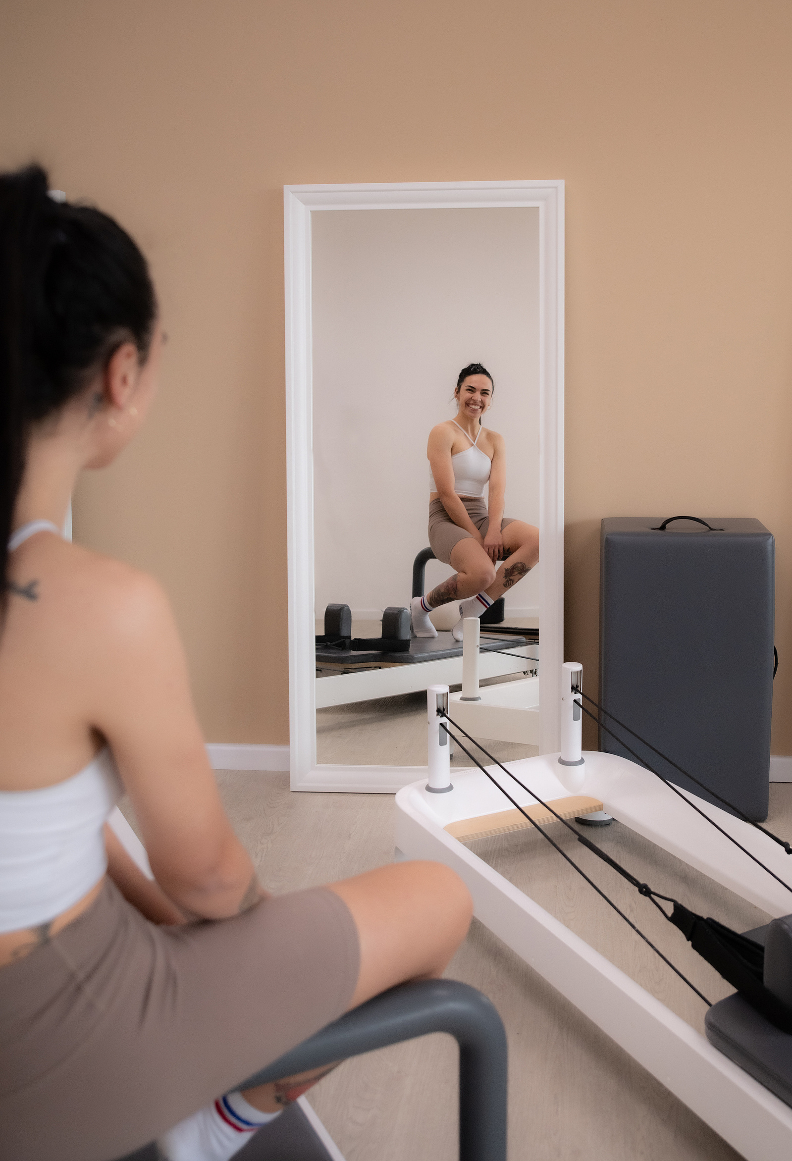 woman looking in mirror next to exercise equipment