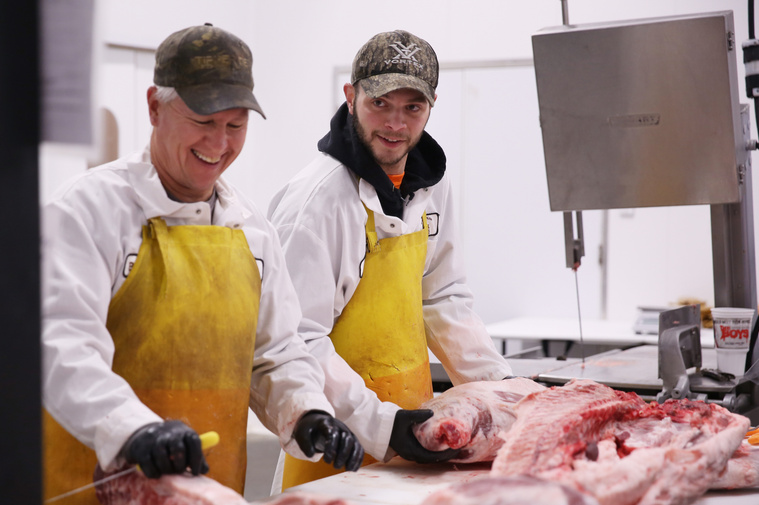 Brandon Purcella, left, and James Miller laugh about a phone call between two of their coworkers while working on a hog on a Saturday morning. The group normally doesn’t work on Saturdays, but because of the high demand this week was an exception.