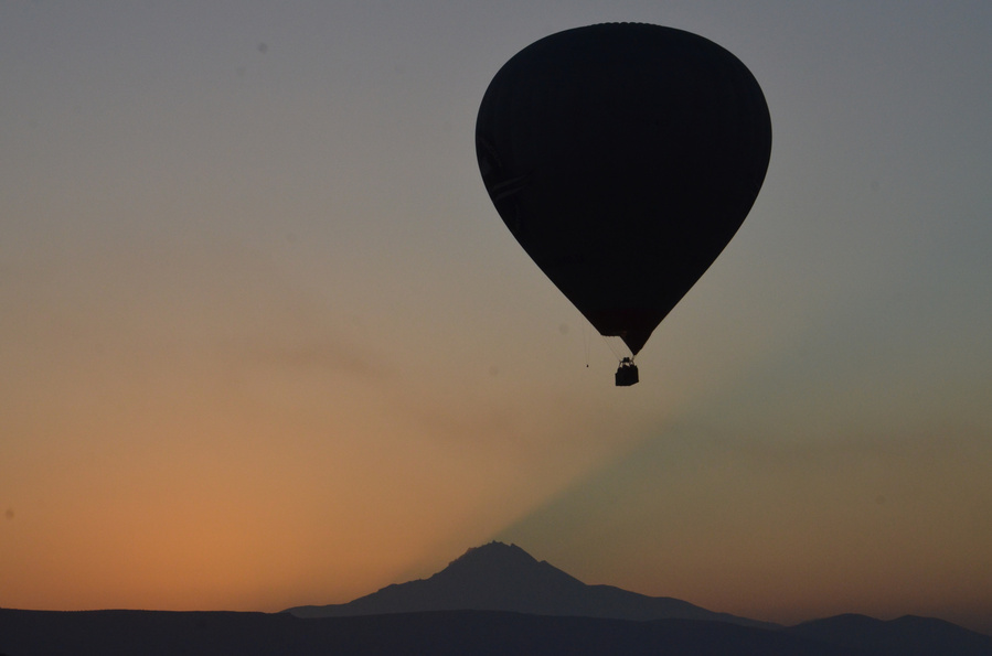 BİR UÇAN  BALON KAPADOKYA SEMALARINDA RÜYASINDA GÜNDOĞUMUNUN ERCİYES DAĞININ ÜZERİNDEN YANSIYAN GÖLGESİNİ GÖRÜYOR