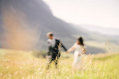 Colorado wedding photographer capturing a bride and groom walking through a mountain field during an outdoor wedding portrait session in Colorado.