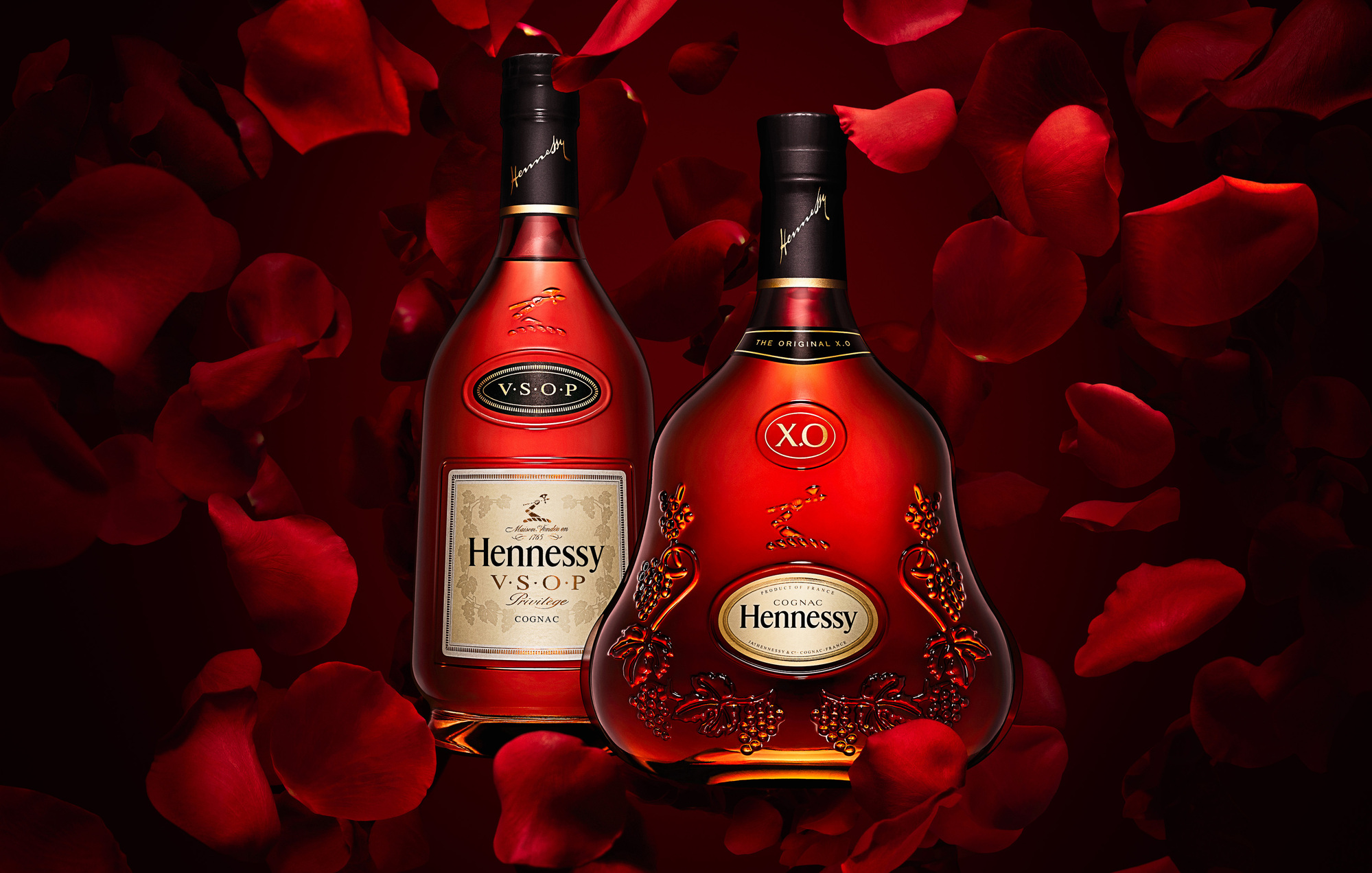Bottles of Hennessy XO  and VSOP Cognac on deep red background with exploding rose petals.  Beverages and alcohol product & advertising photography by Timothy Hogan Studio in Los Angeles