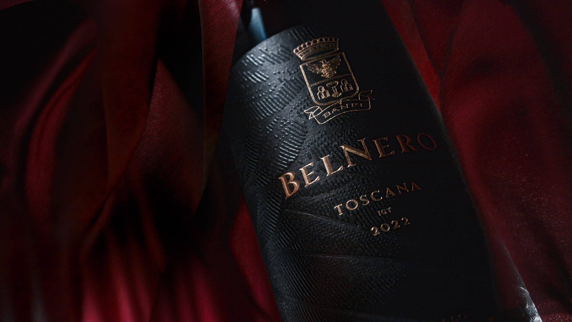 Advertising photography by Timothy Hogan of Banfi Estate Belnero Super Tuscan wine on a black background surrounded by red blowing fabric.