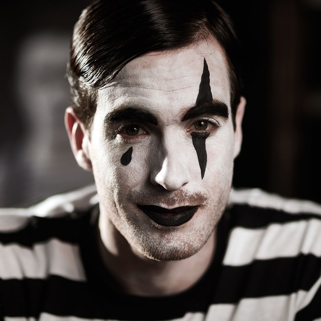 Headshot of a male model wearing clown face paint and a striped t-shirt for an advertising campaign photoshoot. Shot by Norwich commercial, freelance portrait photographer Matt Keal.
