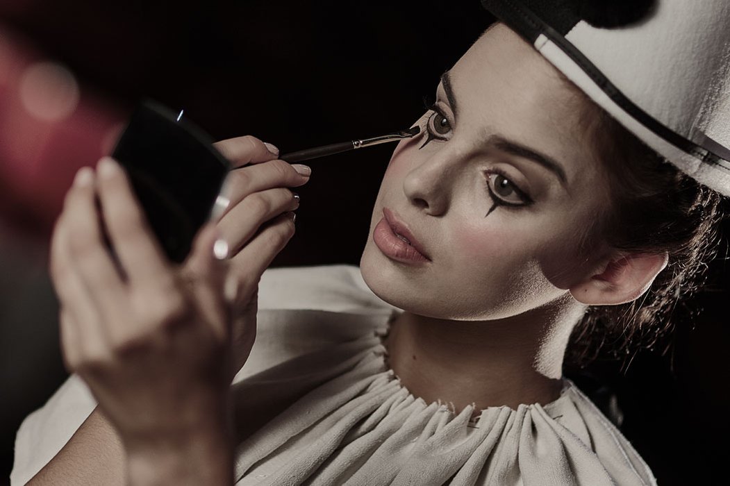 Portrait of a young, female actress applying clown make-up at a commercial website homepage photoshoot. Shot by Norfolk commercial, freelance portrait photographer Matt Keal.
