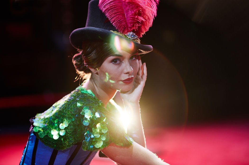 A young female model wearing a circus outfit looks directly into the camera. Shot by Norwich commercial, freelance portrait photographer Matt Keal.