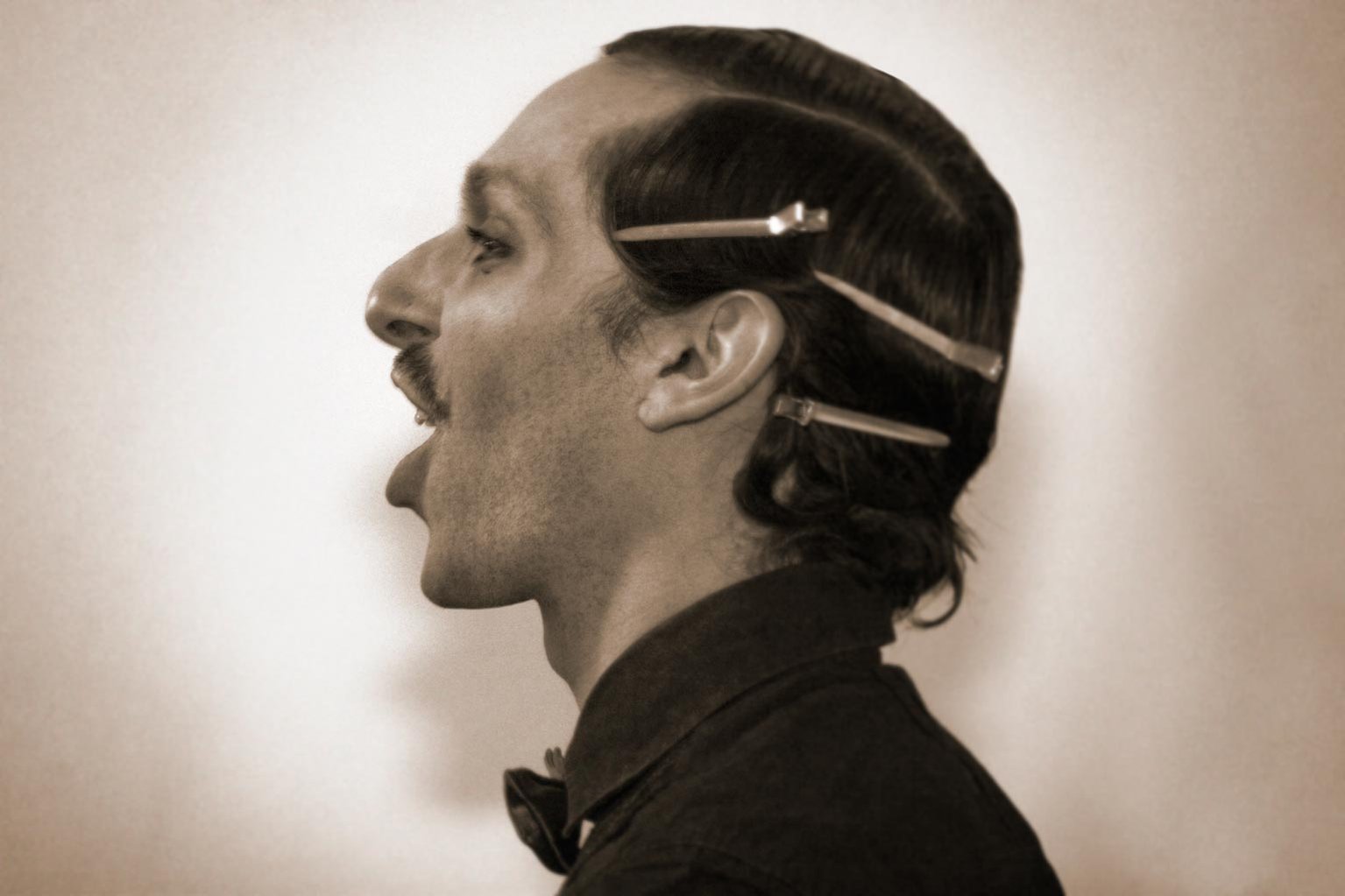 Side-profile portrait of a male model talking with clips in his hair. Shot by Norwich commercial, freelance portrait photographer Matt Keal.