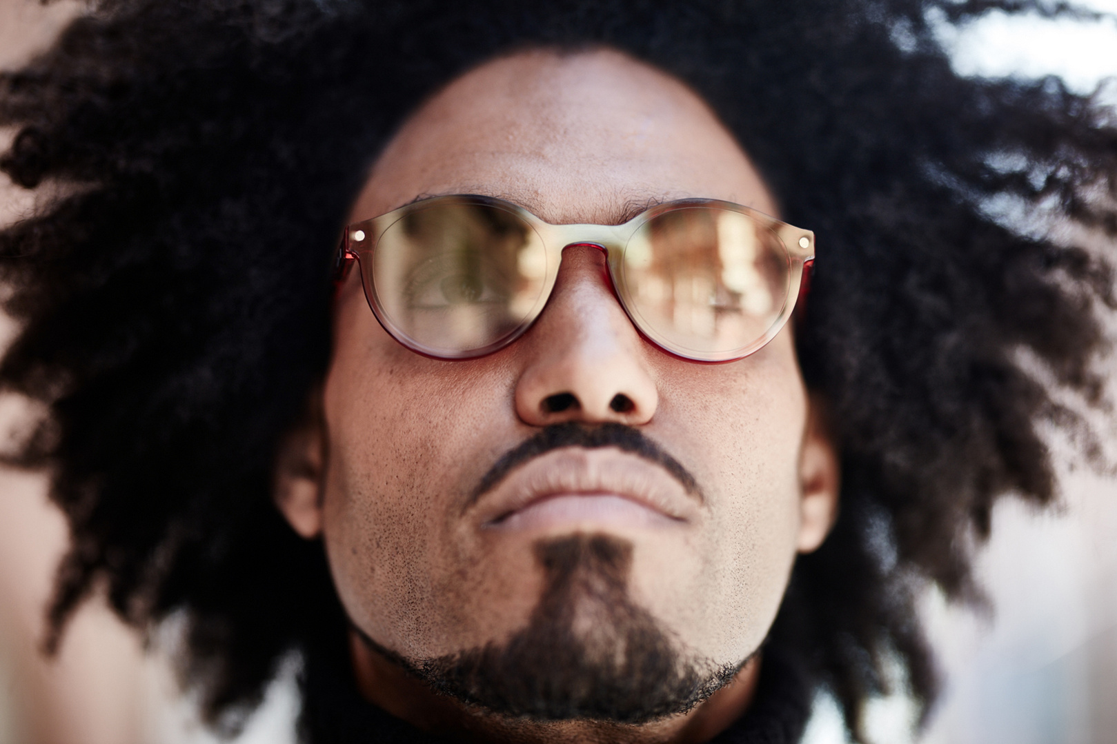 Close-up fashion portrait of a man wearing sunglasses. He has a beard and an afro hairstyle. Shot by Norwich commercial, freelance portrait photographer Matt Keal.