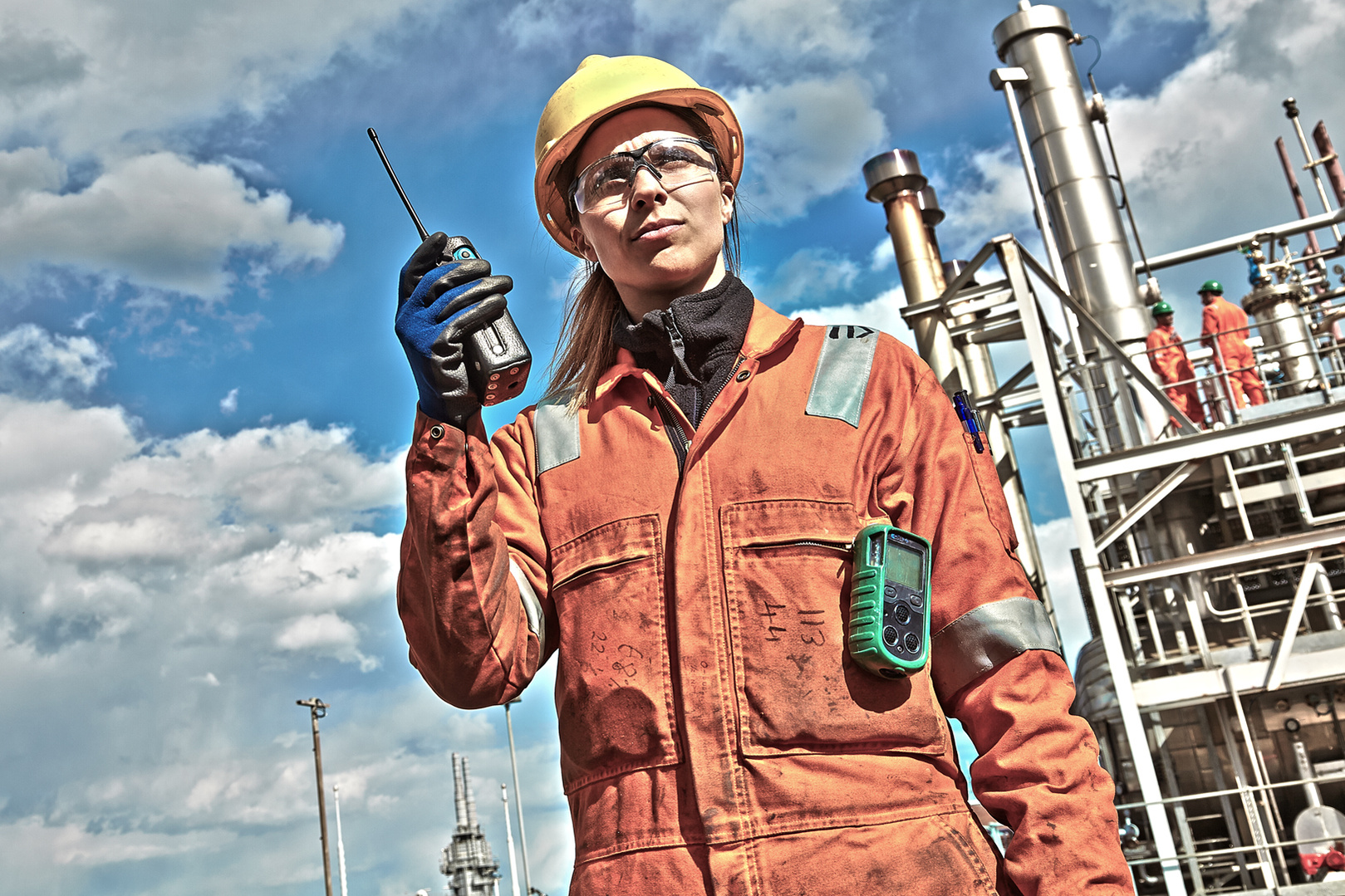 Portrait of a young woman working on a gas refinery using a walkie-talkie wearing hi-vis safety gear. Shot by Norwich commercial, freelance photographer Matt Keal.