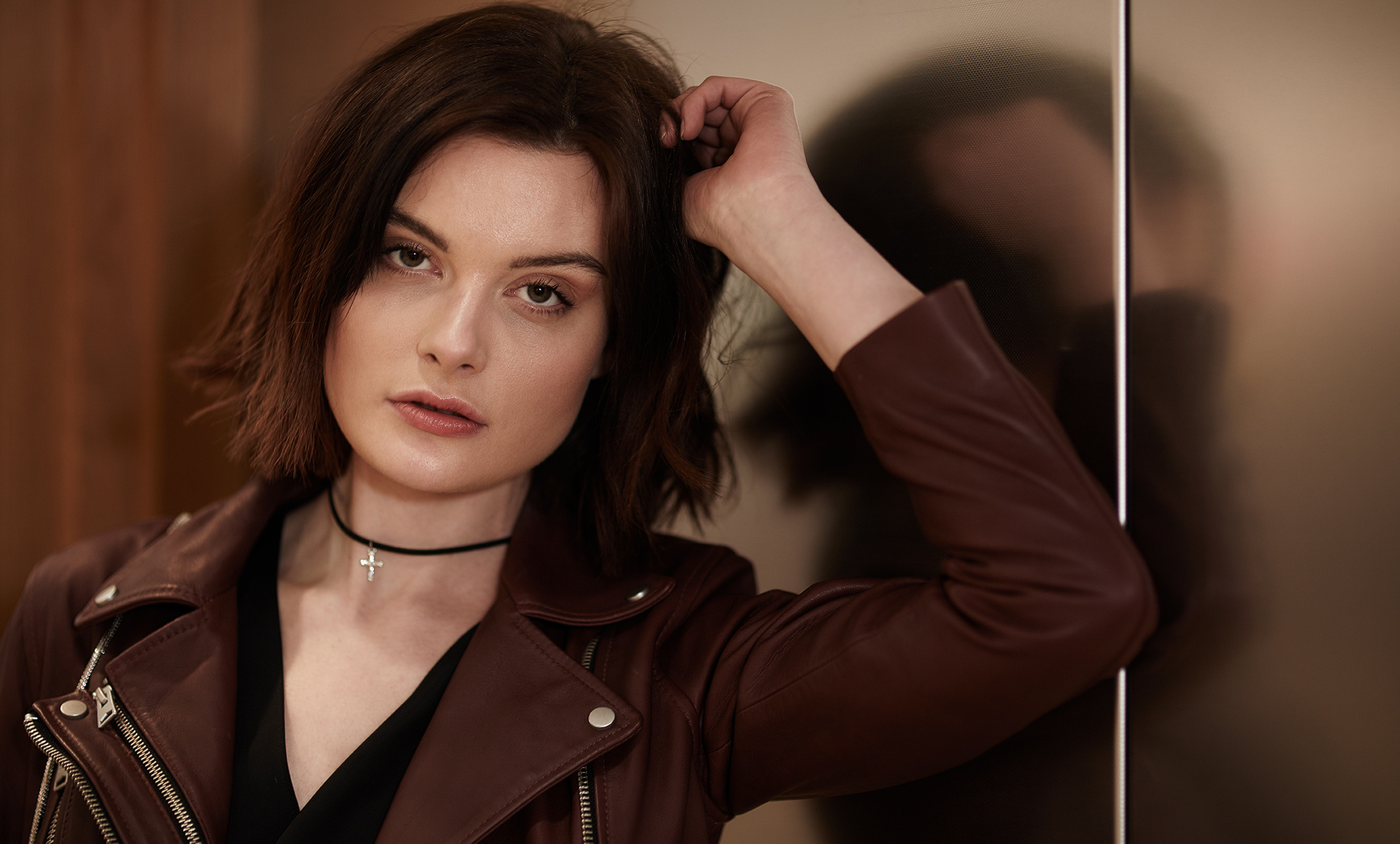 Headshot of a female teenage model looking into the camera and leaning on a reflective surface. She wears a leather jacket and smokey eye makeup. Shot by Norwich commercial, freelance portrait photographer Matt Keal.