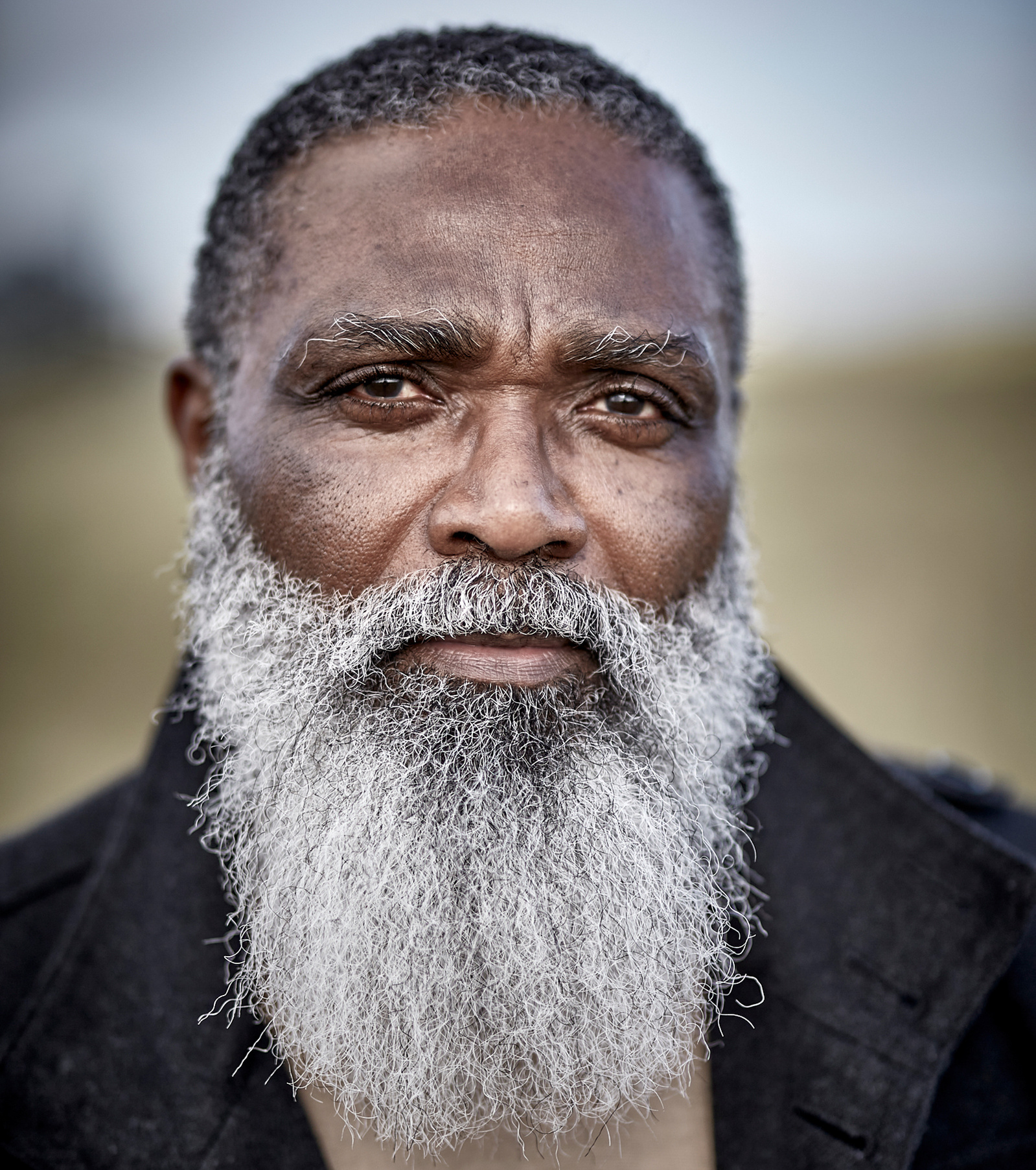 Close-up headshot of a black male model with a large, grey beard at Southwold Beach, Suffolk. Shot by Norwich commercial, freelance portrait photographer Matt Keal.