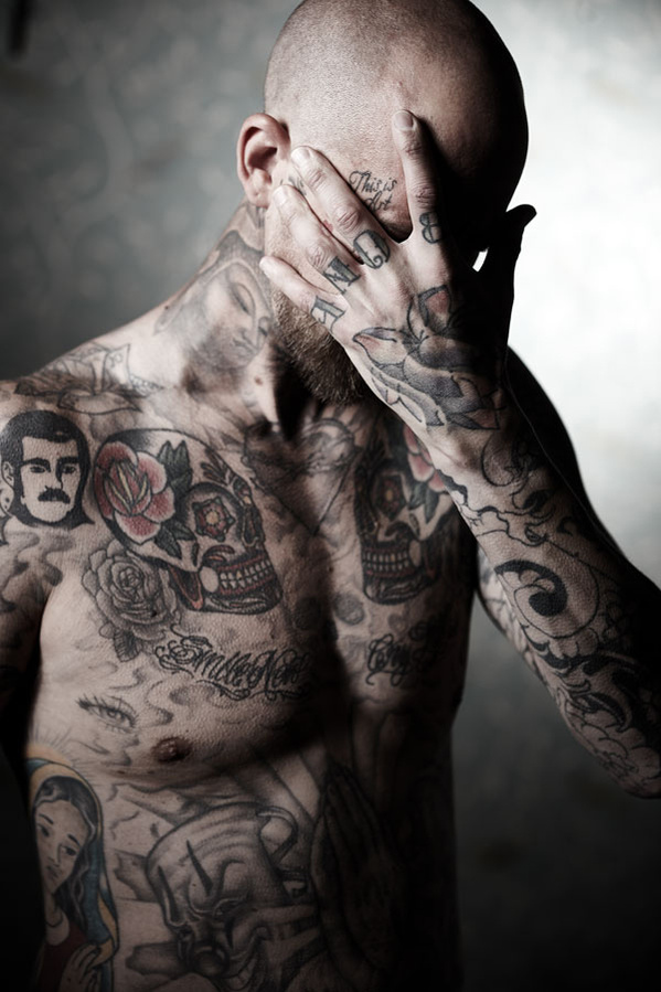 Studio portrait of a tattooed man with his hand covering his face. Shot by Norwich commercial, freelance portrait photographer Matt Keal.