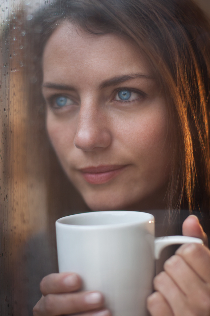 Portrait female model with bright blue eyes looking off into the distance holding a white mug close to her face. Shot by Norwich commercial, freelance portrait photographer Matt Keal.