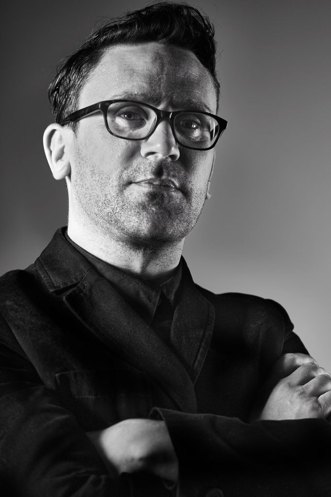 Black and white portrait of a male actor wearing thick black glasses and a black jumper, photographed in Matt Keal's photography studio in Norwich, Norfolk. Shot by Norwich commercial, freelance portrait photographer Matt Keal.