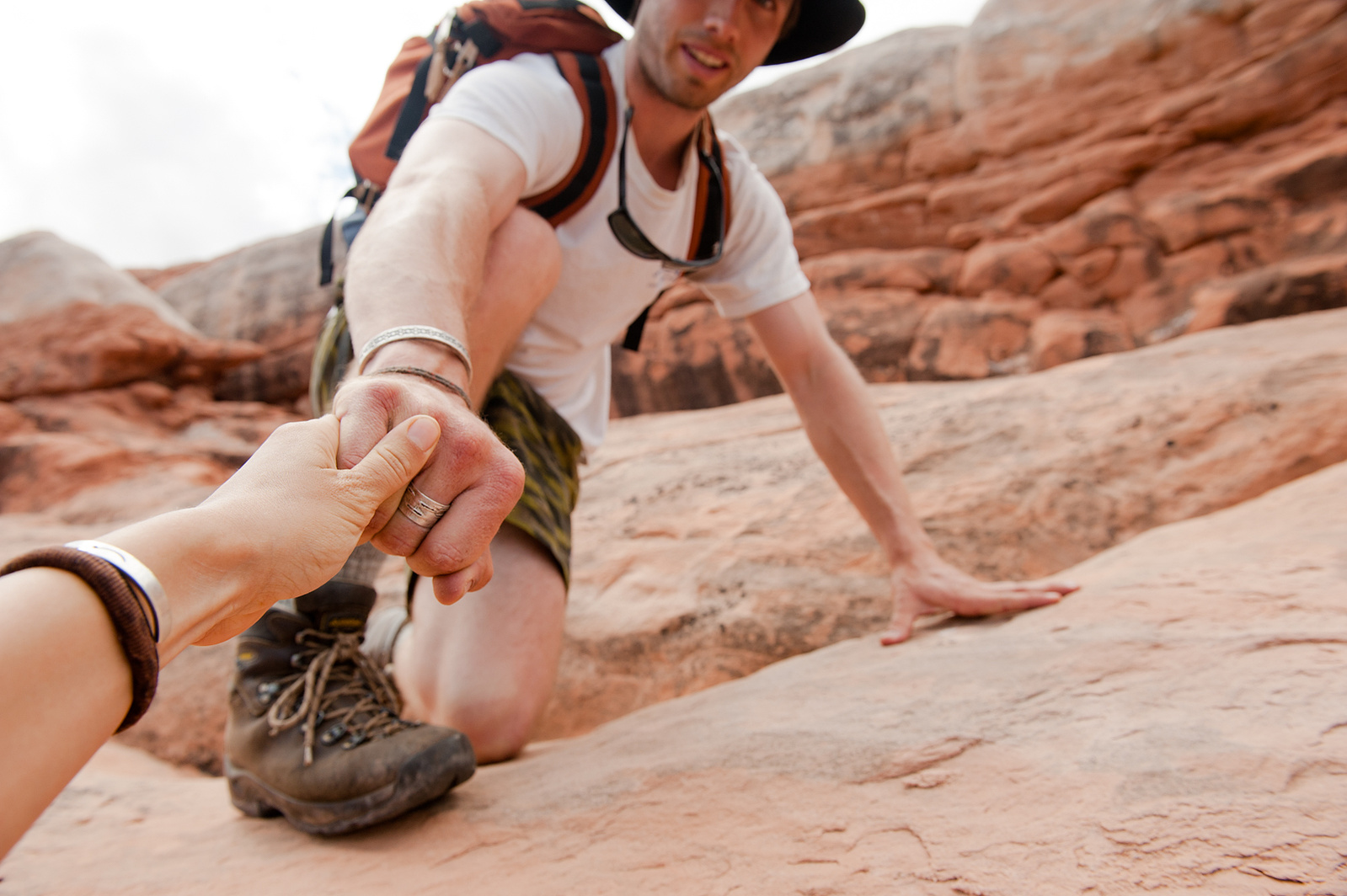 Ecologist Charles Post lending a hand to his hiking partner Meg Haywood Sullivan amongst the red rock outside of Moab, Utah.