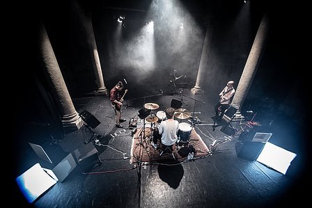 a view from above of a concert stage with instruments and musicians, smoke in the room is creating a hazy view