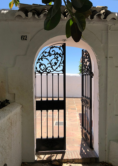Metal gate door nestled in a rounded archway at the property entrance