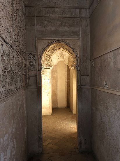 Temple-style interior with solid concrete walls displaying intricate patterns and rounded archways