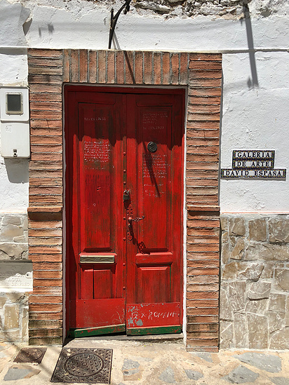 Red door with a brick archway on the exterior of a white and beige brick house