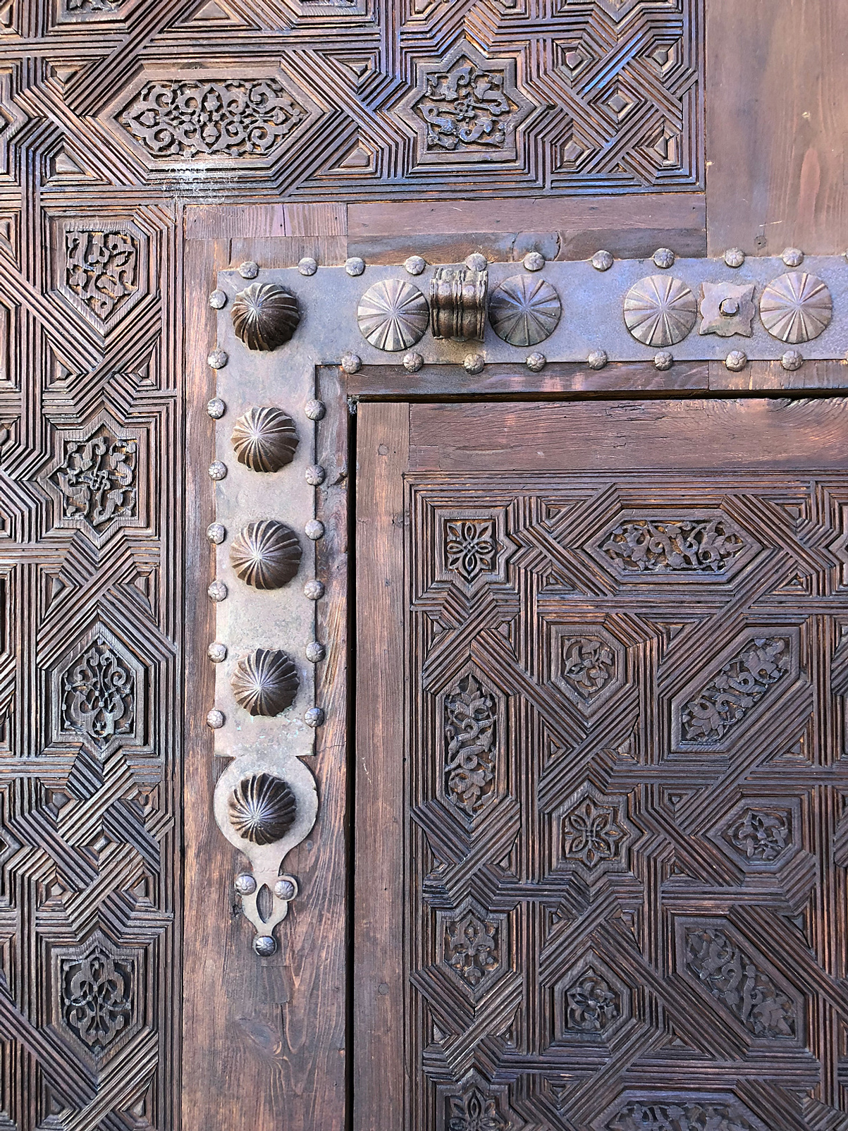 Intricate symmetrical carvings on a large dark wooden door