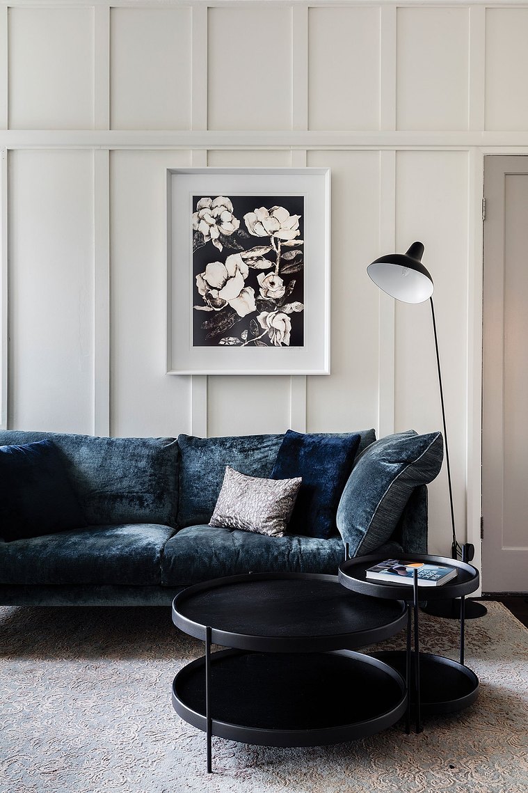 White and rustic living room space with a suede navy couch and monochromatic elements surrounding it