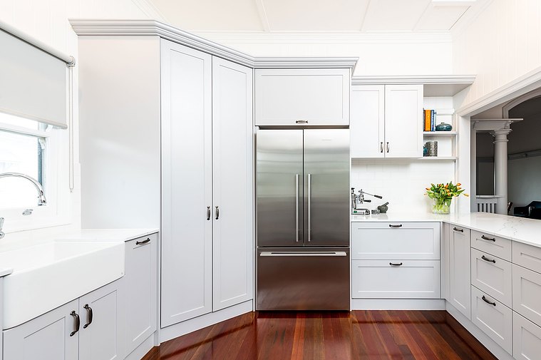 White, modern kitchen space with stainless steel fridge and colourful, minimalistic decorations