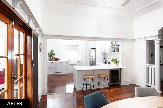 White, open concept kitchen with wooden barstools and floors