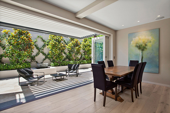 Open air dining room with a wooden table and floral artwork hanging on the wall