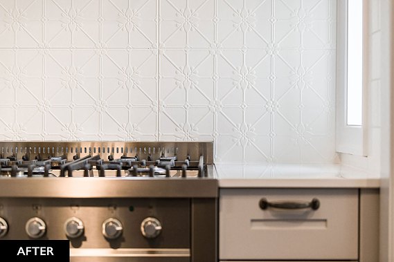 Stainless steel gas stove with white patterned wall behind