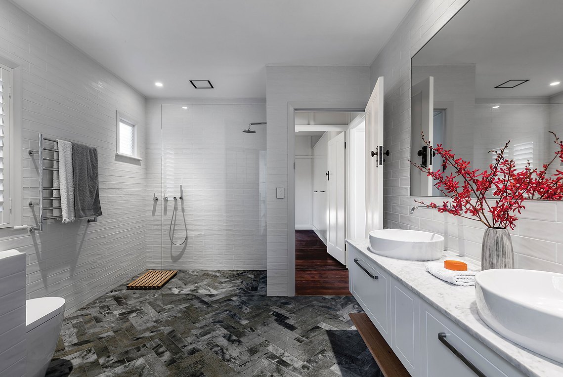 White and minimalistic bathroom with an open concept shower and two, round, modern sinks