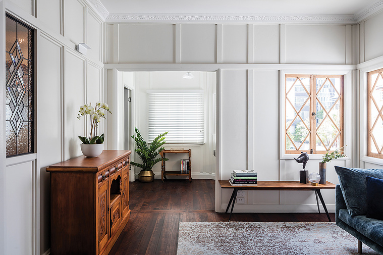White and rustic living room space with a suede navy couch and wooden features throughout
