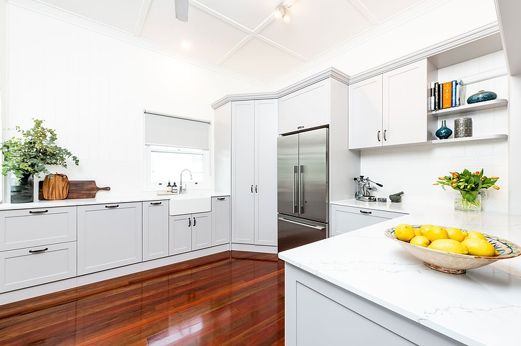 White, modern kitchen space with stainless steel fridge and colourful, minimalistic decorations