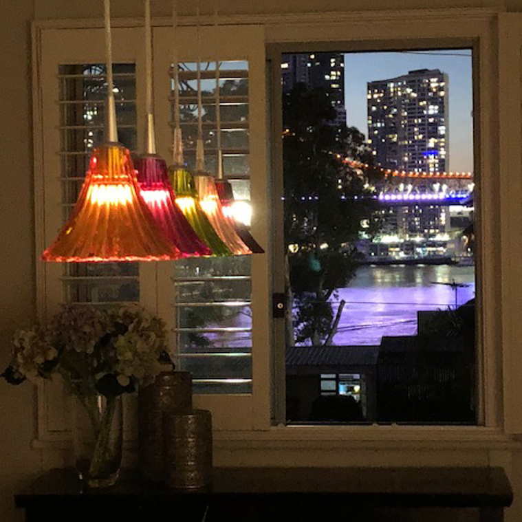 Colourful hanging lamps in a dining room with a view of the Brisbane story bridge in the background