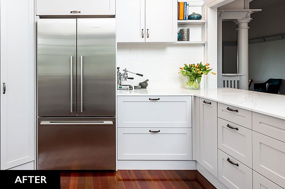 White, open concept kitchen with wooden floors and a stainless steel fridge