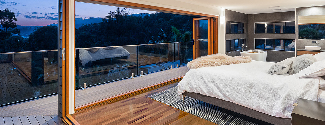Bedroom with glass windows and a balcony overlooking Upper Coomera landscapes