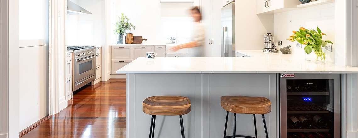 White, open concept kitchen with wooden barstools and floors