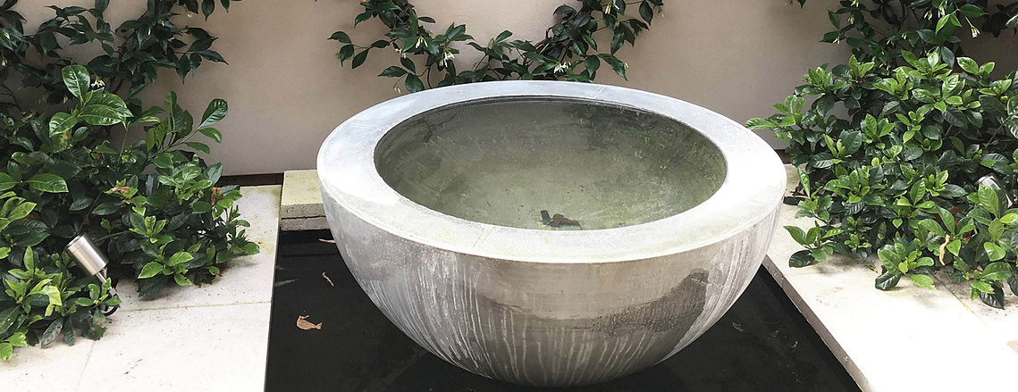 Half sphere water fountain feature surrounded by greenery