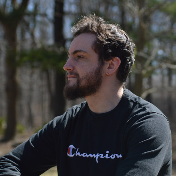 Headshot of myself sitting in a park looking off camera to the left.