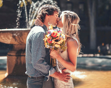 A bride and a groom are kissing in front of a fountain, North End, Boston.